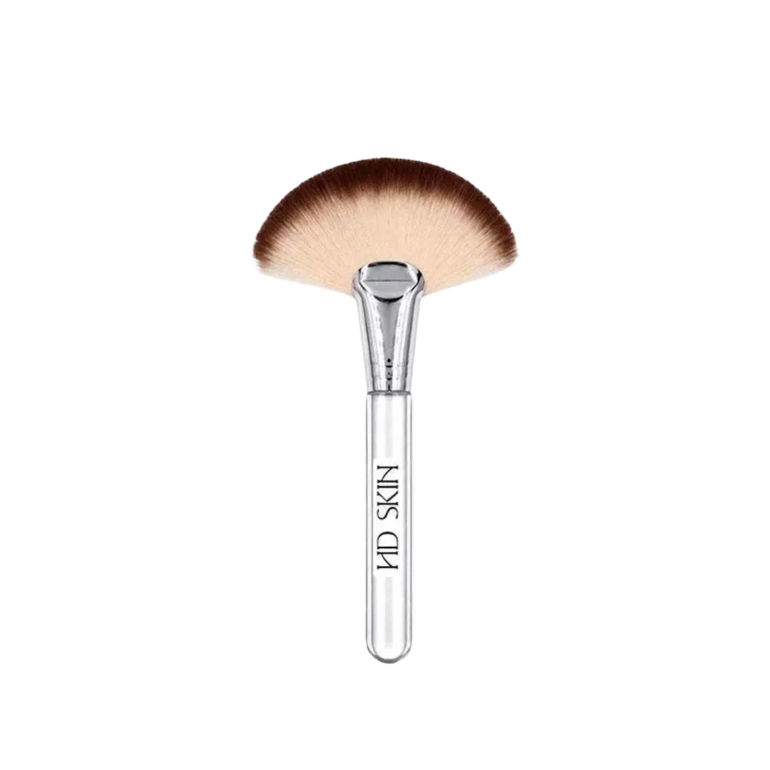The Fluff Brush facial cleansing brush with a clear handle and fan-shaped soft bristles in gradient brown and cream tones